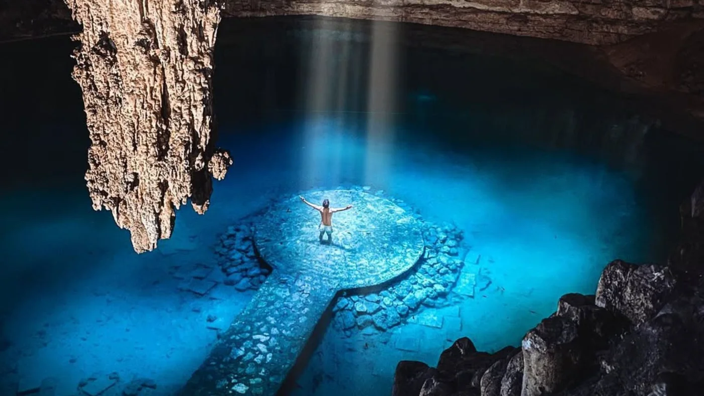Cave cenote with a shaft of daylight over turquoise water